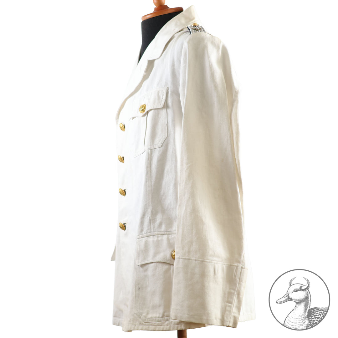 Weißes Jackett (nach neuer Vorschrift) der Kriegsmarine für einen Leutnant der
Küstenartillerie . Das Jackett besitzt aufgesetzte Brust- und Seitentaschen mit Quetschfalten. Die
feuervergoldeten Ankerknöpfe sind sicher mit Sprengringen angebracht, während der
vorschriftsmäßige Metallbrustadler mittels typischer Zwirnschlaufen befestigt ist. Innen finden sich ein Größen- und Herstellerstempel sowie die Namensstickerei
„Hadenfeld“