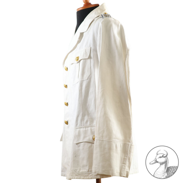 Weißes Jackett (nach neuer Vorschrift) der Kriegsmarine für einen Leutnant der
Küstenartillerie . Das Jackett besitzt aufgesetzte Brust- und Seitentaschen mit Quetschfalten. Die
feuervergoldeten Ankerknöpfe sind sicher mit Sprengringen angebracht, während der
vorschriftsmäßige Metallbrustadler mittels typischer Zwirnschlaufen befestigt ist. Innen finden sich ein Größen- und Herstellerstempel sowie die Namensstickerei
„Hadenfeld“