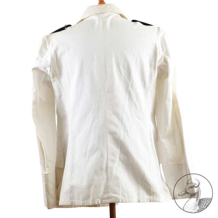 Weißes Jackett (nach neuer Vorschrift) der Kriegsmarine für einen Leutnant der
Küstenartillerie . Das Jackett besitzt aufgesetzte Brust- und Seitentaschen mit Quetschfalten. Die
feuervergoldeten Ankerknöpfe sind sicher mit Sprengringen angebracht, während der
vorschriftsmäßige Metallbrustadler mittels typischer Zwirnschlaufen befestigt ist. Innen finden sich ein Größen- und Herstellerstempel sowie die Namensstickerei
„Hadenfeld“