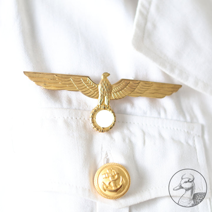 Weißes Jackett (nach neuer Vorschrift) der Kriegsmarine für einen Leutnant der
Küstenartillerie . Das Jackett besitzt aufgesetzte Brust- und Seitentaschen mit Quetschfalten. Die
feuervergoldeten Ankerknöpfe sind sicher mit Sprengringen angebracht, während der
vorschriftsmäßige Metallbrustadler mittels typischer Zwirnschlaufen befestigt ist. Innen finden sich ein Größen- und Herstellerstempel sowie die Namensstickerei
„Hadenfeld“