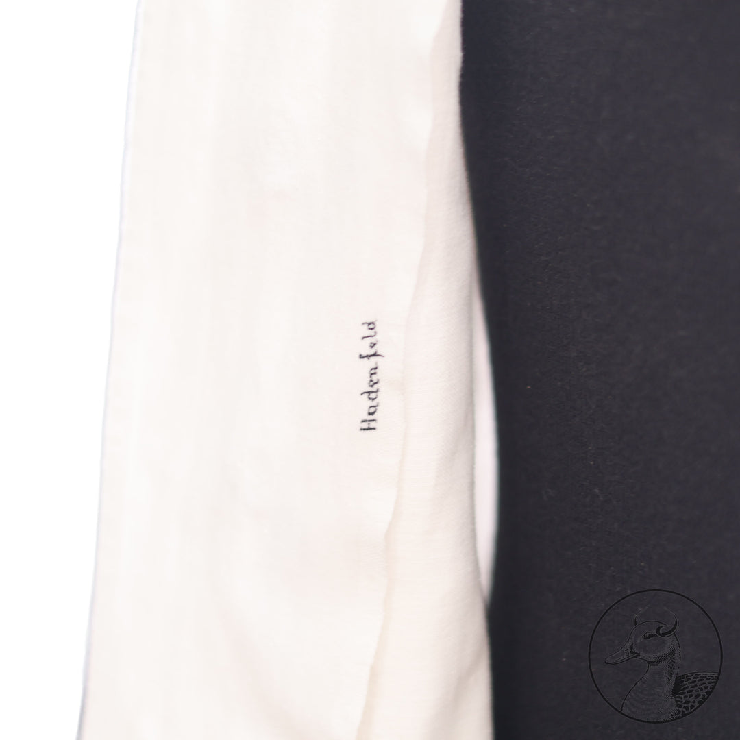 Weißes Jackett (nach neuer Vorschrift) der Kriegsmarine für einen Leutnant der
Küstenartillerie . Das Jackett besitzt aufgesetzte Brust- und Seitentaschen mit Quetschfalten. Die
feuervergoldeten Ankerknöpfe sind sicher mit Sprengringen angebracht, während der
vorschriftsmäßige Metallbrustadler mittels typischer Zwirnschlaufen befestigt ist. Innen finden sich ein Größen- und Herstellerstempel sowie die Namensstickerei
„Hadenfeld“