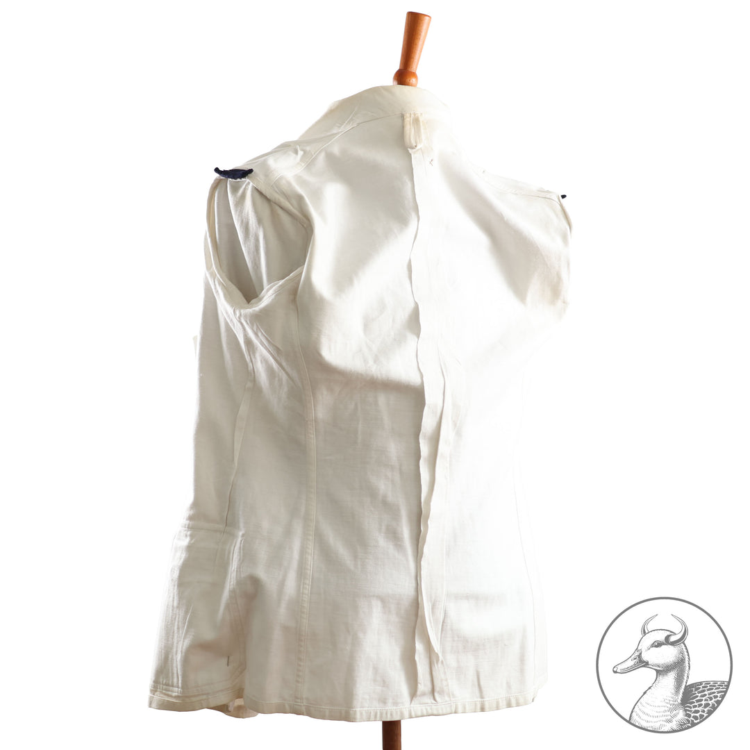 Weißes Jackett (nach neuer Vorschrift) der Kriegsmarine für einen Leutnant der
Küstenartillerie . Das Jackett besitzt aufgesetzte Brust- und Seitentaschen mit Quetschfalten. Die
feuervergoldeten Ankerknöpfe sind sicher mit Sprengringen angebracht, während der
vorschriftsmäßige Metallbrustadler mittels typischer Zwirnschlaufen befestigt ist. Innen finden sich ein Größen- und Herstellerstempel sowie die Namensstickerei
„Hadenfeld“