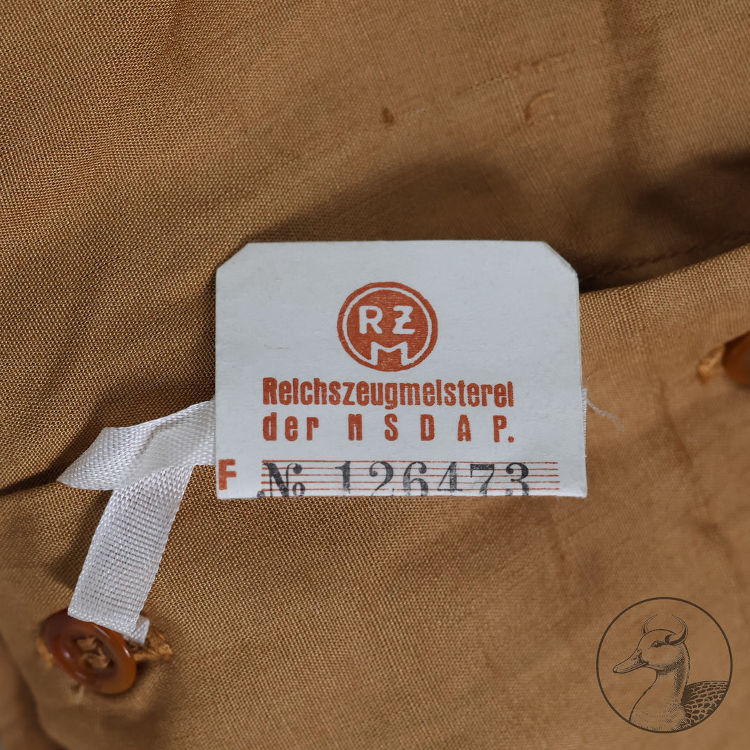 Originales Braunhemd der Partei NSDAP mit Wechselkragen

Hemd aus feiner Baumwolle und knöpfbarem Wechselkragen.
Mit RZM-Etikett "RZM Reichszeugmeisterei der NSDAP" und altem Preisschild RM: 10,96
Das Braunhemd wurde als Diensthemd unter dem Dienstrock getragen.