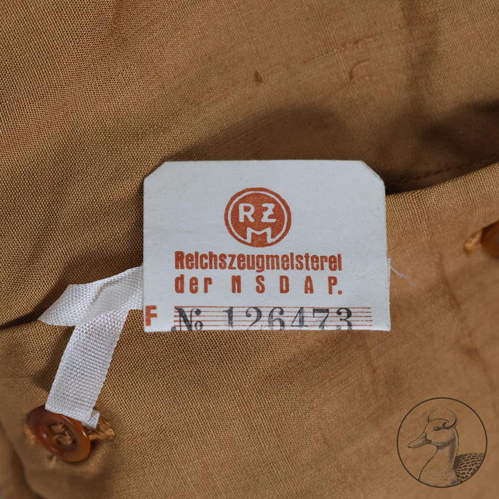 Originales Braunhemd der Partei NSDAP mit Wechselkragen

Hemd aus feiner Baumwolle und knöpfbarem Wechselkragen.
Mit RZM-Etikett "RZM Reichszeugmeisterei der NSDAP" und altem Preisschild RM: 10,96
Das Braunhemd wurde als Diensthemd unter dem Dienstrock getragen.