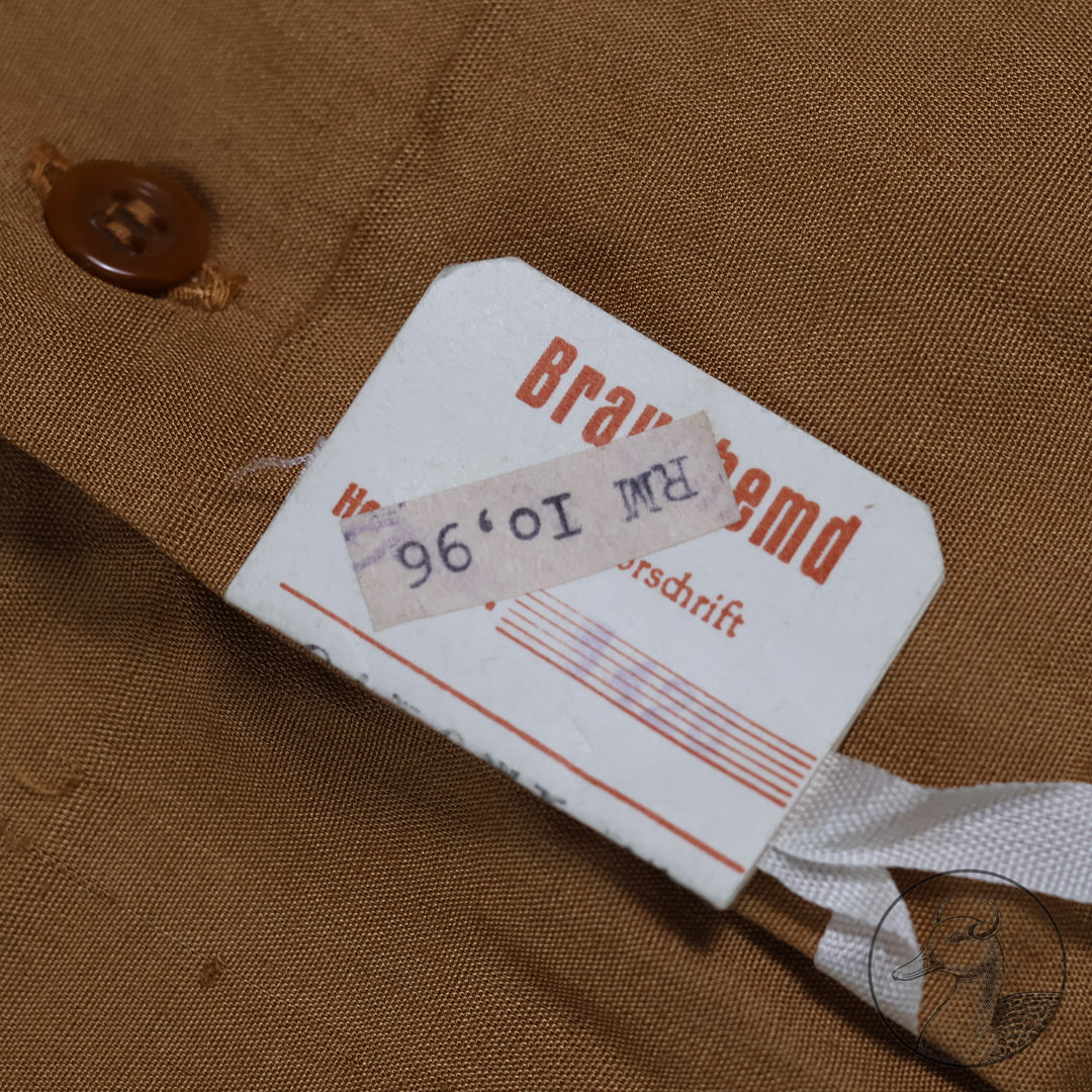 Originales Braunhemd der Partei NSDAP mit Wechselkragen

Hemd aus feiner Baumwolle und knöpfbarem Wechselkragen.
Mit RZM-Etikett "RZM Reichszeugmeisterei der NSDAP" und altem Preisschild RM: 10,96
Das Braunhemd wurde als Diensthemd unter dem Dienstrock getragen.